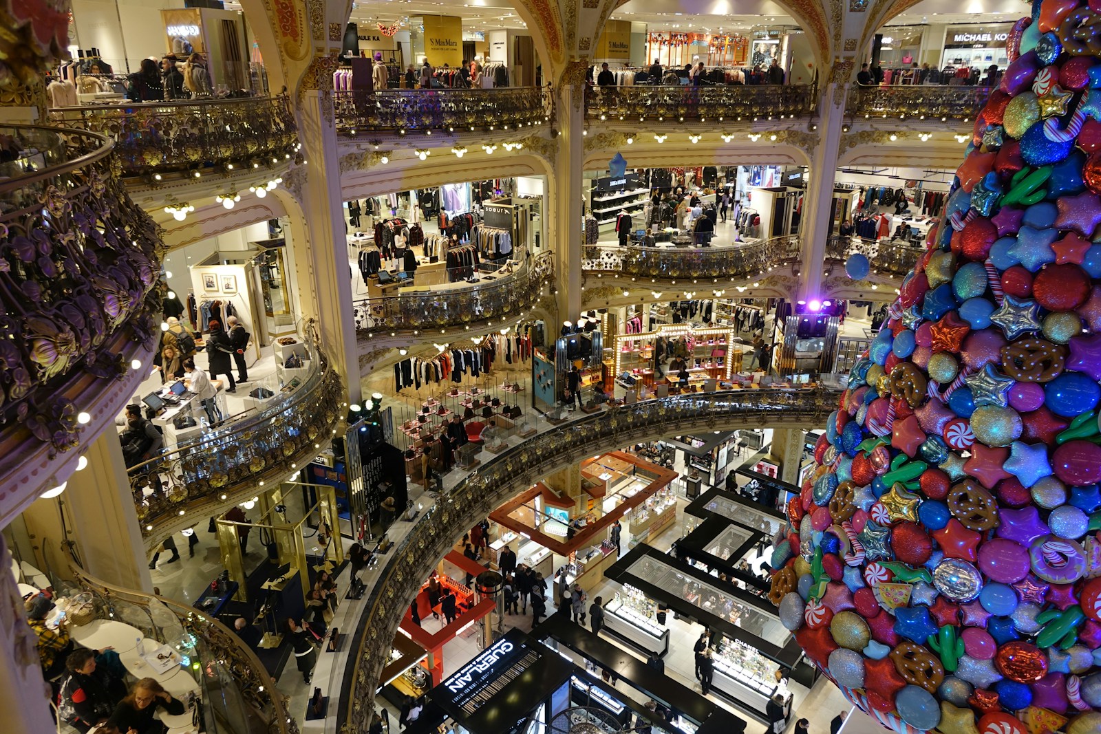 A large christmas tree in a mall filled with people